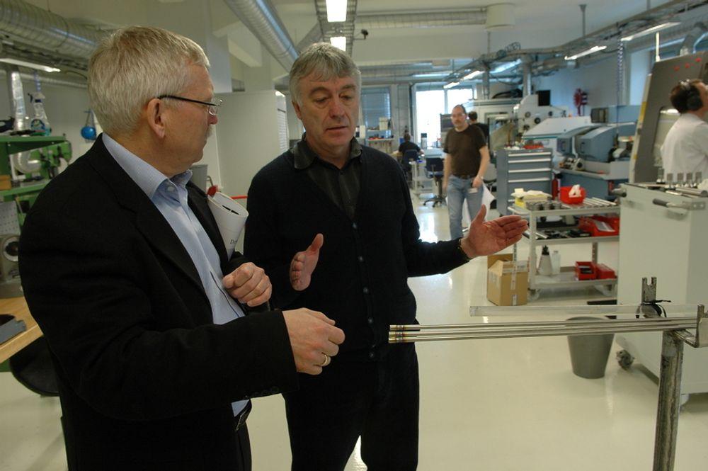 MINIATYR: Forskningsdirektørene Fritjov Øwre og Wolfgang Wiesenack studerer instrumentlaboratoriet. De tynne rørene brukes i oppsett for instrumentering inne i reaktorkjernen. De er på samme diameter som  brenselstavene i reaktoren.
