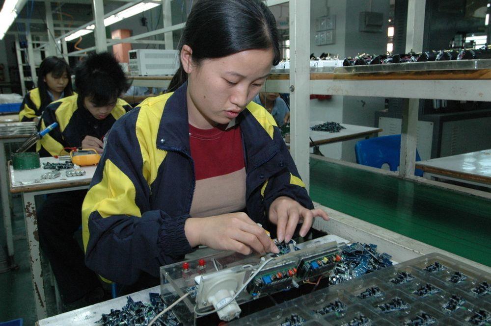 TJENER 7 KR: Yin Ai Xiang er og de andre arbeidere ved produksjonslinja arbeider konsentrert med å sette sammen en høyttaler til iPod. Lønna er sju kroner i timen.