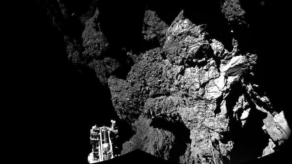 Her er Philae mens den står på bakken av kometen. Den ene foten til landeren kan skimtes nede til venstre.