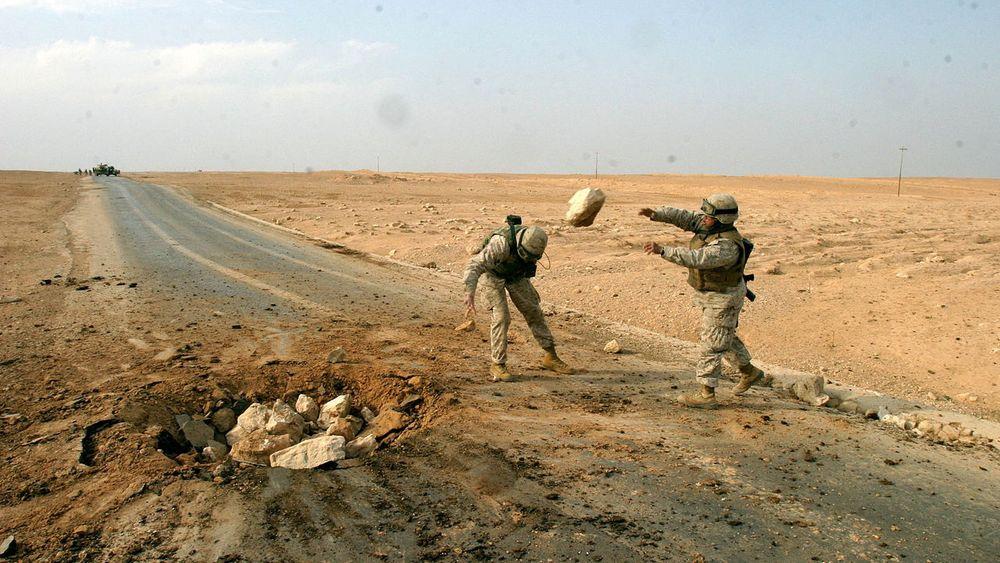 Soldater fra USAs marinekorps rydder opp etter en landmineeksplosjon på en vei i Al Qaim i Irak.