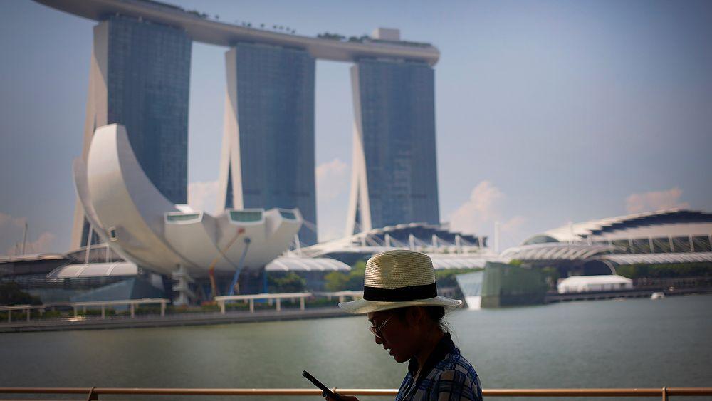 En turist sjekker smarttelefonen i Marina Bay Sands, Singapore. Byen er på topp i smartbyundersøkelser. Men på noen områder ligger Norge foran.