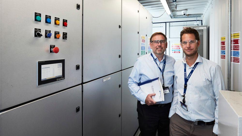 Teknisk produktsjef for energilagringssystemet Save Energy, Jens Hjorteset (t.h) og plassjef Erling Johannesen ved Rolls-Royce avdeling for Power Electric Systems i Bergen i det første komplette hybridsystemet, bygget i en container.