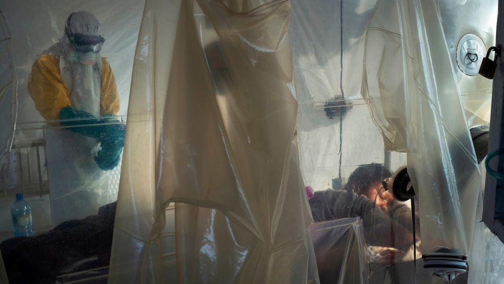 Helsepersonell iført beskyttelsesutstyr undersøker en pasient som ligger i isolat ved et behandlingssenter for ebola i Beni i Kongo. 