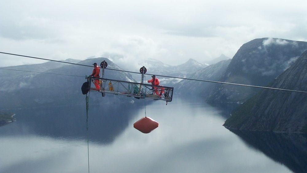 Man kan ikke ha høydeskrekk hvis man skal bygge eller vedlikeholde kraftlinjer. Men nå mener NVE og Energi Norge at også prisen er for høy. Bilder er fra utskifting av flymarkører over Hellemofjorden i 2003.