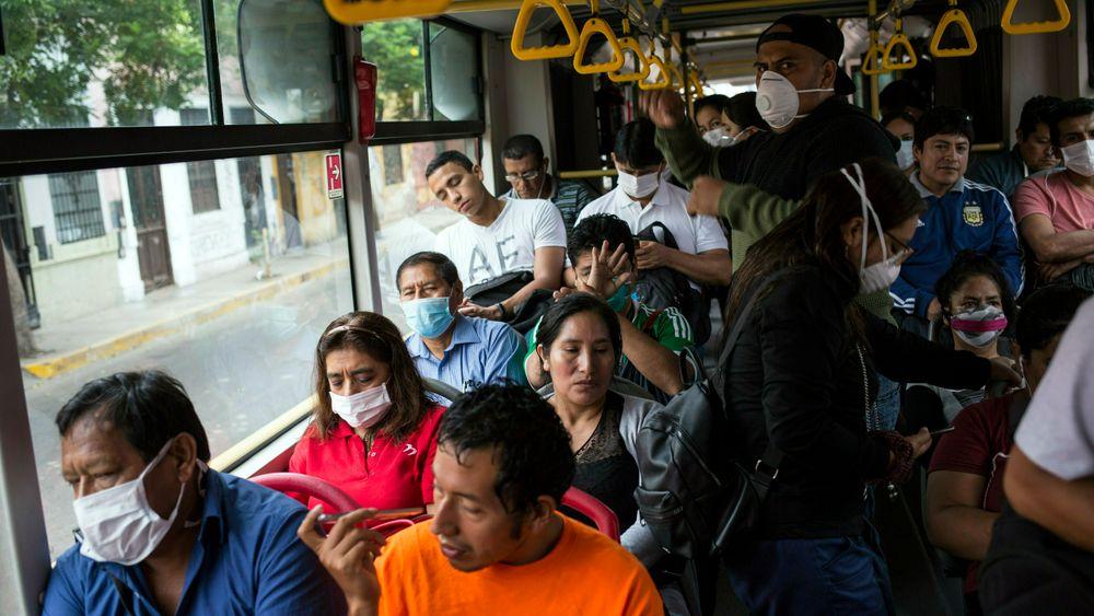 Passasjerer med munnbind på en buss i Perus hovedstad Lima. Landet erklærte mandag unntakstilstand.