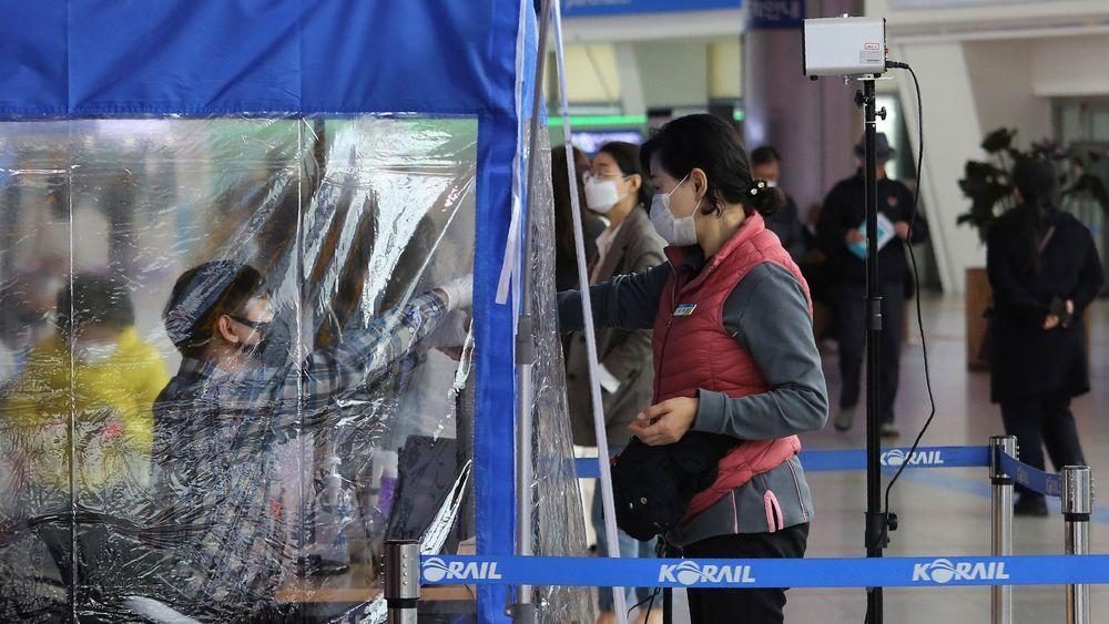 En kvinne som ønsker å ta toget fra Seoul, får temperaturen sjekket av en togansatt før ombordstigning. Sør-Korea har testet svært mange innbyggere for koronavirus og symptomer.