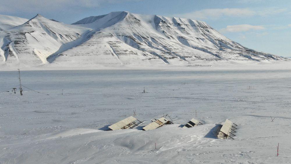Feltforsøk på Svalbard undersøker potensialet og utfordringer for bakkemonterte solkraftverk. Her ser vi anlegget tidlig på våren når strømproduksjonen akkurat har begynt. Én rad er delvis begravd i snøfonner.