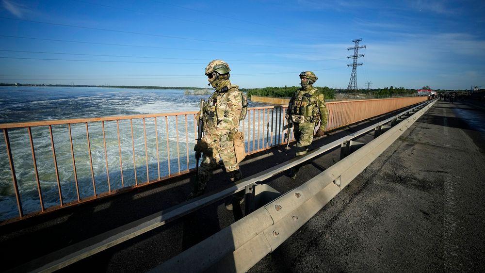 Russiske soldater patruljerer rundt demningen til vannkraftverket i Kakhovka.